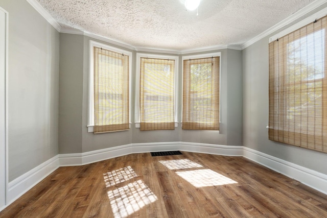 spare room featuring a textured ceiling, crown molding, and dark wood-type flooring