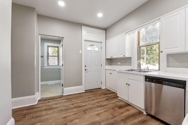 kitchen with hardwood / wood-style flooring, stainless steel dishwasher, white cabinetry, and sink