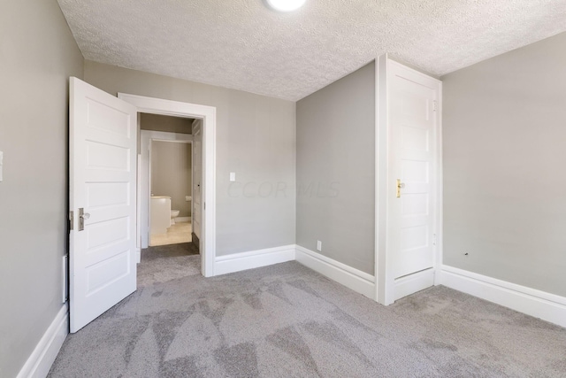 unfurnished bedroom featuring light carpet and a textured ceiling