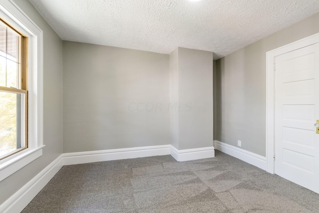 carpeted spare room with a textured ceiling