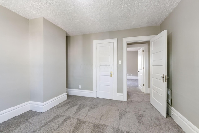 unfurnished bedroom featuring light carpet and a textured ceiling