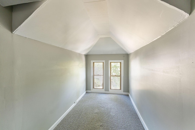 carpeted spare room with vaulted ceiling