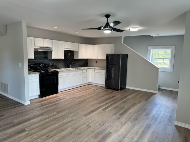 kitchen featuring sink, light hardwood / wood-style floors, decorative backsplash, white cabinets, and black appliances