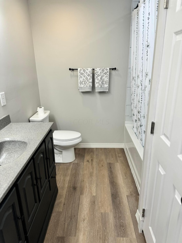 full bathroom with shower / bath combination with curtain, vanity, hardwood / wood-style flooring, and toilet