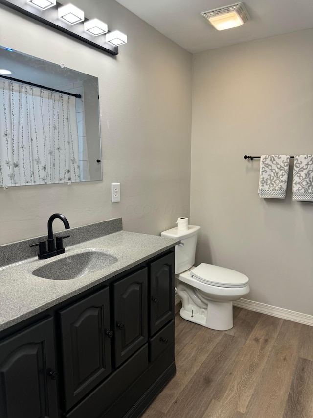 bathroom with toilet, vanity, and hardwood / wood-style flooring