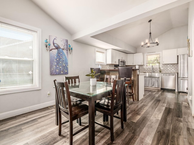 dining area featuring wood-type flooring, an inviting chandelier, lofted ceiling, and sink