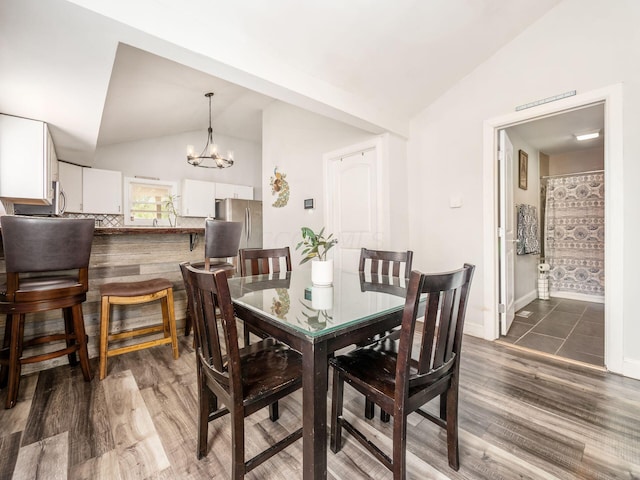 dining space with lofted ceiling, a chandelier, and dark hardwood / wood-style floors