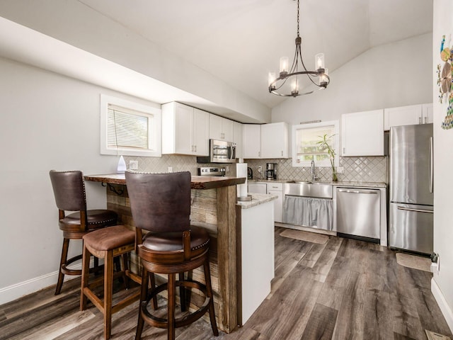 kitchen with dark wood-type flooring, white cabinets, sink, a breakfast bar area, and stainless steel appliances