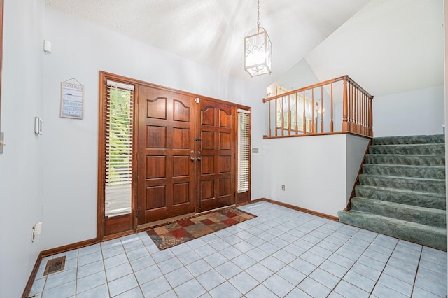 tiled entryway featuring a textured ceiling, lofted ceiling, and an inviting chandelier