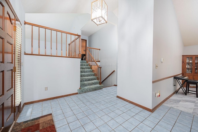 tiled entrance foyer featuring an inviting chandelier and high vaulted ceiling