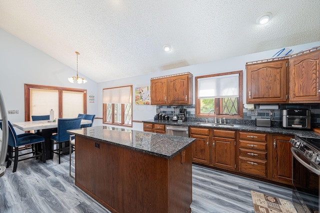 kitchen featuring stainless steel appliances, sink, an inviting chandelier, hardwood / wood-style floors, and lofted ceiling