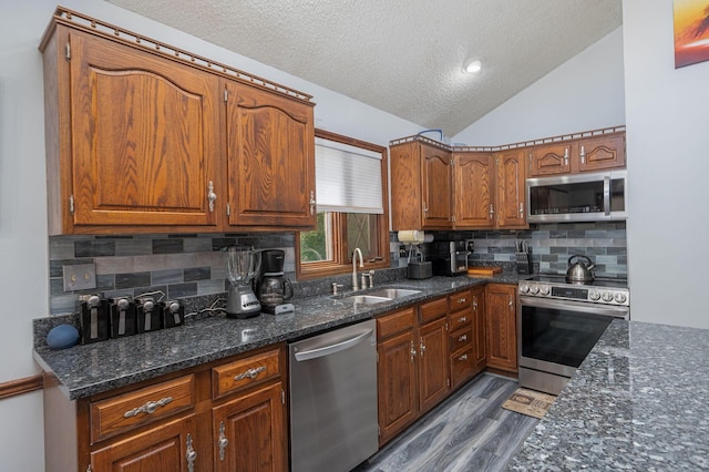 kitchen with appliances with stainless steel finishes, backsplash, lofted ceiling, and sink