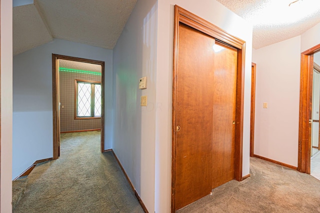 corridor featuring carpet, a textured ceiling, and lofted ceiling