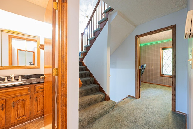 staircase featuring a textured ceiling, carpet floors, sink, and vaulted ceiling