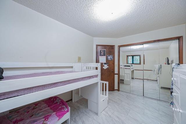 bedroom with washer and clothes dryer, a textured ceiling, and a closet