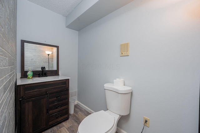 bathroom with hardwood / wood-style floors, vanity, toilet, and a textured ceiling