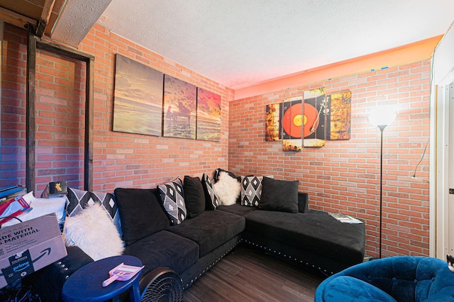 living room with hardwood / wood-style floors, brick wall, and a textured ceiling