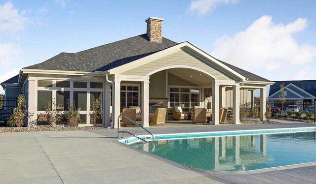 back of house with a fenced in pool, a chimney, roof with shingles, a patio area, and outdoor lounge area