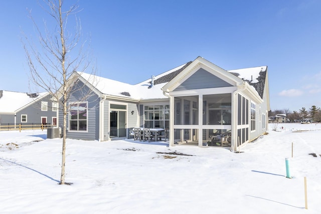 snow covered rear of property featuring a sunroom and central AC