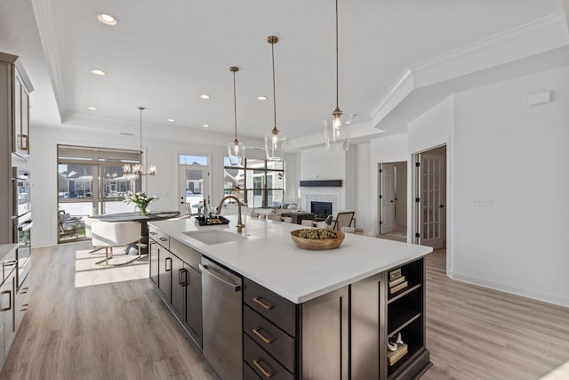 kitchen featuring stainless steel appliances, a fireplace, a sink, light countertops, and light wood-type flooring