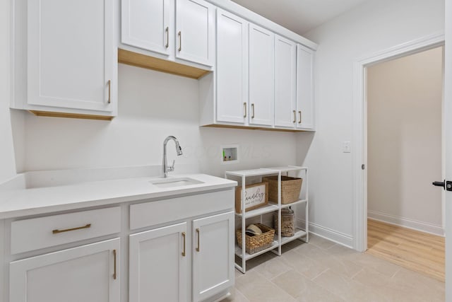 washroom with baseboards, a sink, cabinet space, and hookup for a washing machine