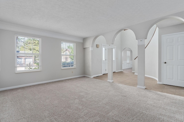 carpeted spare room with a textured ceiling and ornate columns