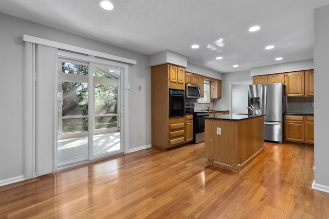 kitchen featuring backsplash, stainless steel appliances, sink, light hardwood / wood-style flooring, and a center island