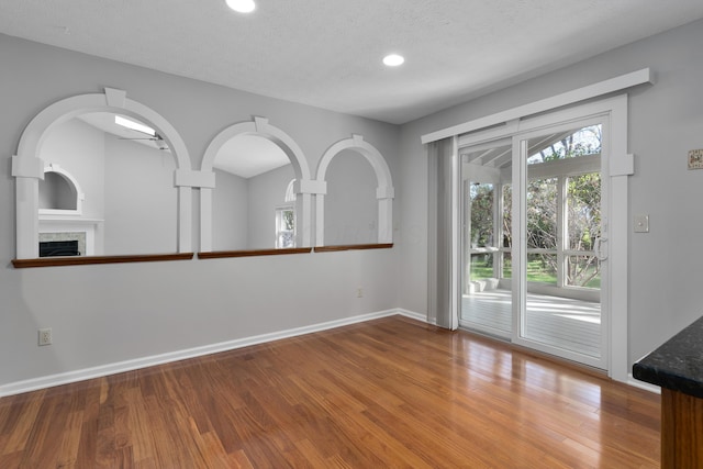 unfurnished room with a tiled fireplace, a textured ceiling, and hardwood / wood-style flooring