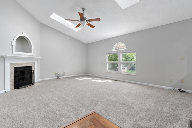 unfurnished living room with carpet, lofted ceiling with skylight, ceiling fan, a textured ceiling, and a tiled fireplace