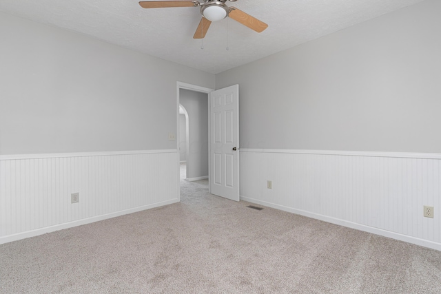 carpeted spare room featuring ceiling fan and a textured ceiling