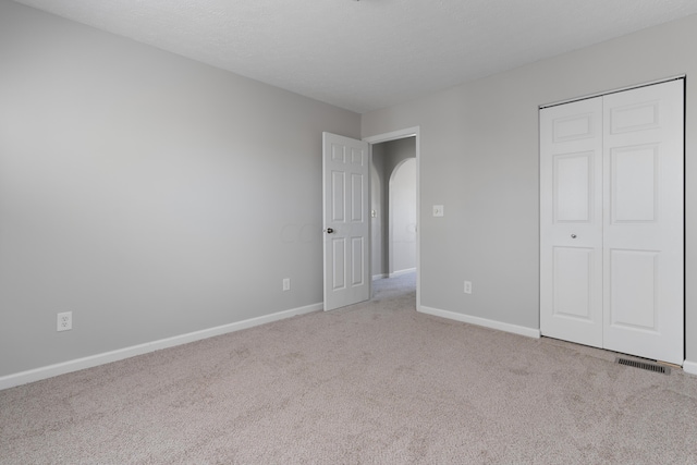 unfurnished bedroom featuring light colored carpet and a closet