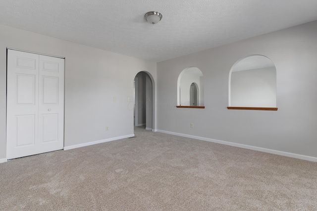 spare room featuring light carpet and a textured ceiling