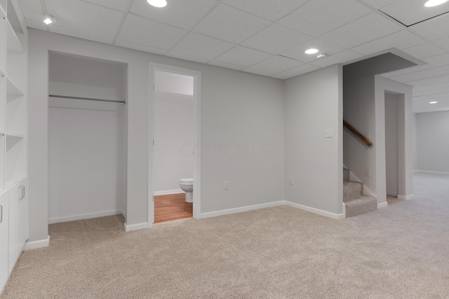 basement with a drop ceiling and light carpet