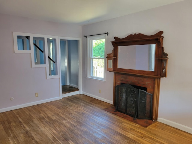 unfurnished living room with hardwood / wood-style floors and a brick fireplace