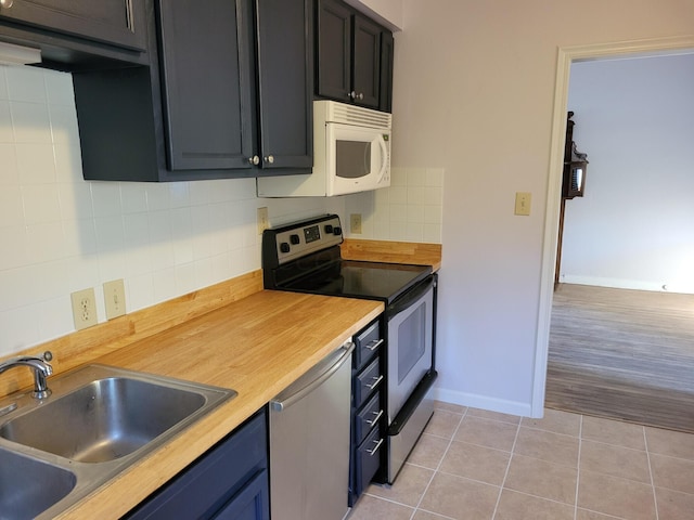 kitchen featuring sink, stainless steel appliances, tasteful backsplash, wooden counters, and light hardwood / wood-style floors