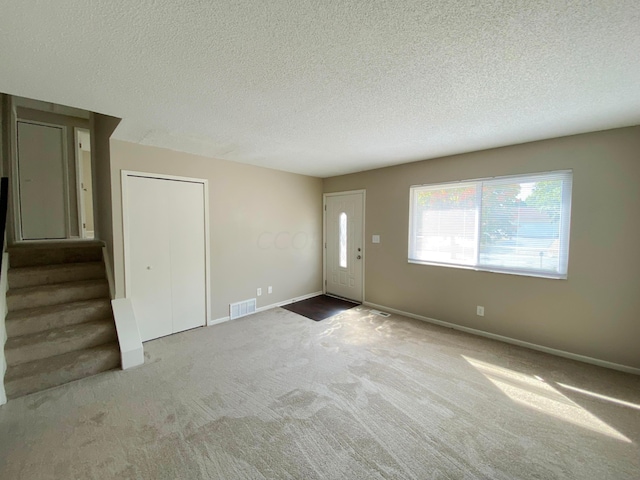 unfurnished living room with a textured ceiling and light carpet