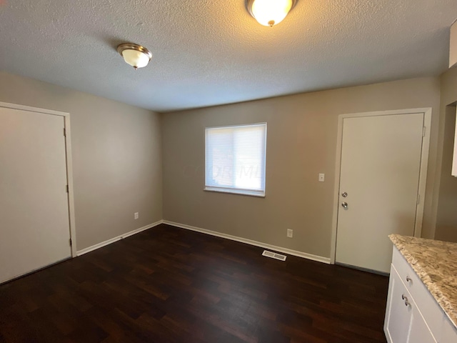 empty room featuring dark wood-type flooring and a textured ceiling