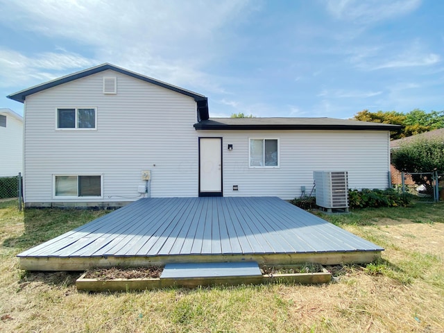 rear view of property featuring a deck, a yard, and cooling unit