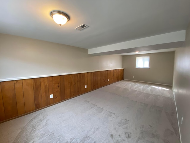 basement featuring wooden walls and light carpet