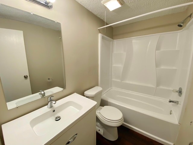 full bathroom featuring toilet, a textured ceiling, washtub / shower combination, hardwood / wood-style floors, and vanity