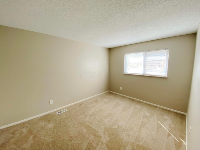 unfurnished room featuring a textured ceiling and light carpet