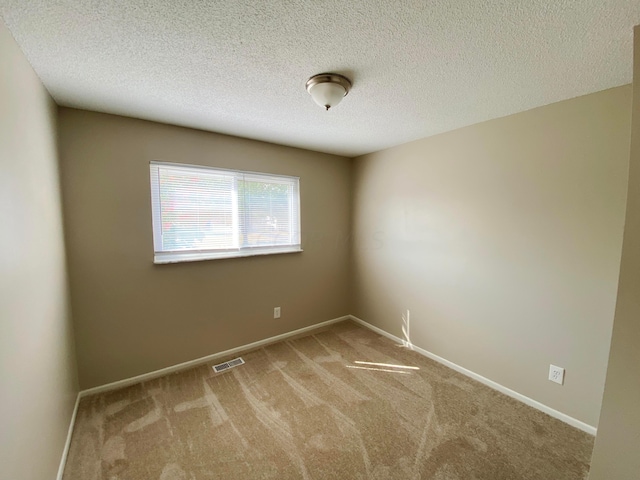 carpeted empty room with a textured ceiling