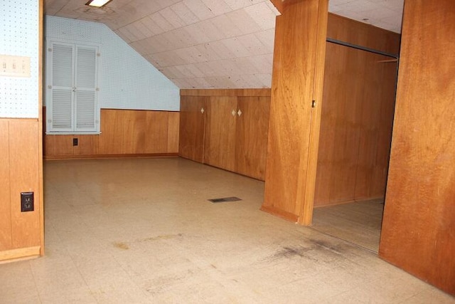 bonus room featuring lofted ceiling and wooden walls