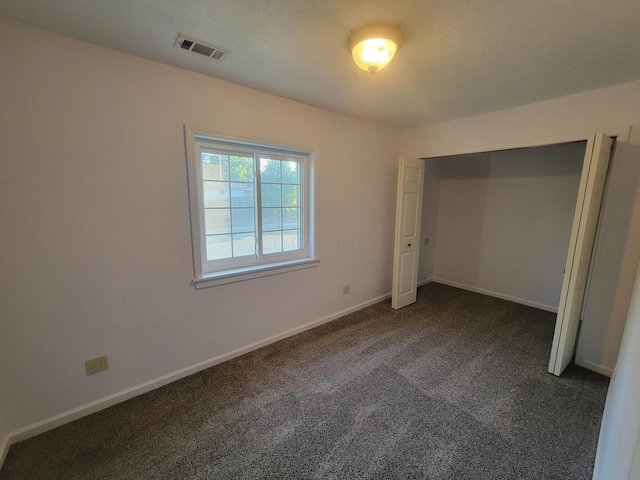 unfurnished bedroom featuring a closet and dark colored carpet