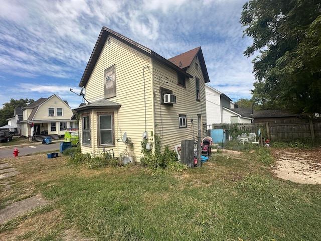 view of home's exterior with a lawn and a wall unit AC