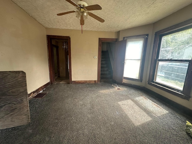 unfurnished room featuring ceiling fan, a textured ceiling, and dark colored carpet