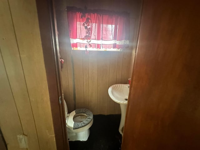 bathroom featuring wood walls and toilet