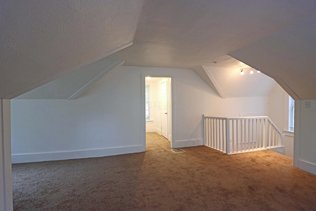 bonus room with a textured ceiling, carpet floors, and lofted ceiling