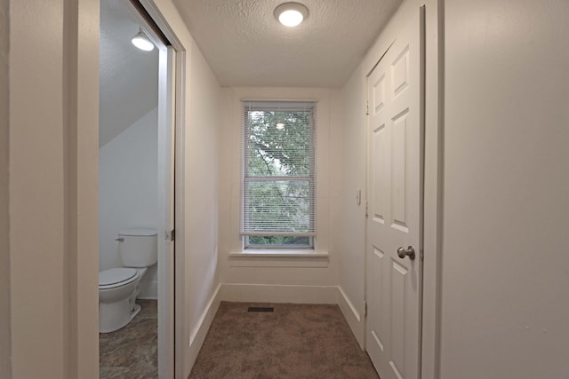 interior space featuring a textured ceiling and dark carpet