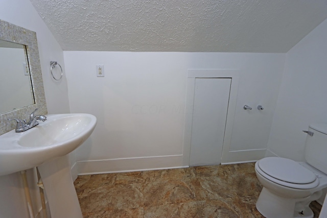 bathroom featuring toilet, lofted ceiling, and a textured ceiling